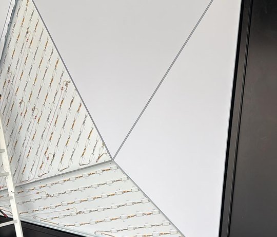 Wand während der Montage: rechts fertig bespannte Pyramidenflächen, links zwei offene Flächen mit der LED-Matrix dahinter